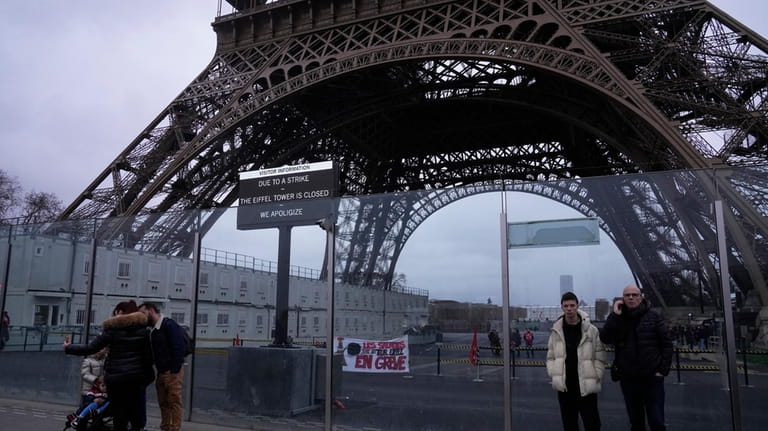 People stand outside the Eiffel Tower Monday, Feb. 19, 2024...