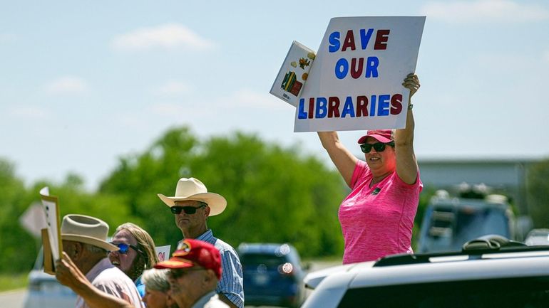 A resident protests outside a Llano County Commissioner's Court meeting...