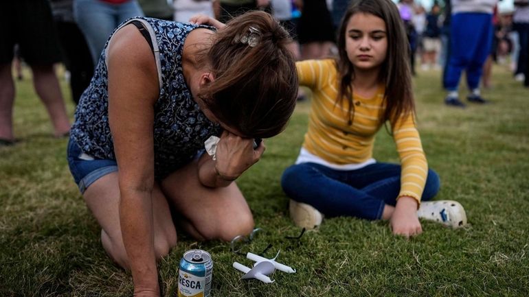 Brandy Rickaba and her daughter Emilie pray during a candlelight...