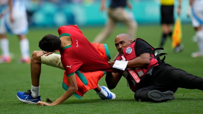 A steward catches a pitch invader during the men's Group...