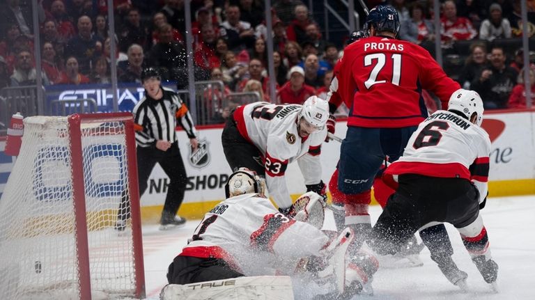 Ottawa Senators goaltender Anton Forsberg, bottom left, watches the puck...