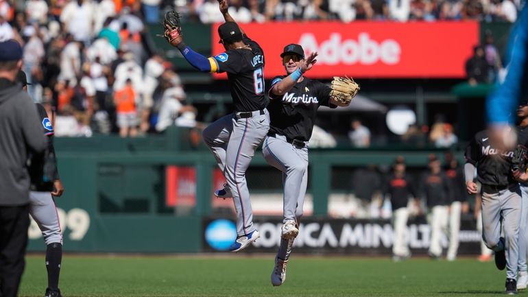 Miami Marlins shortstop Otto Lopez, cemter left, and left fielder...