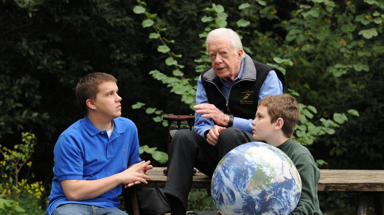 Jimmy Carter walks with his grandsons Jeremy Carter, right, 22,...