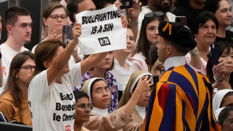 A woman holds up a placard reading "Bullfighting is a...