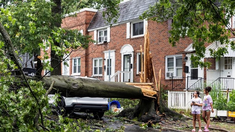 Children survey damage on Adrian Street in Harrisburg, Pa., after...