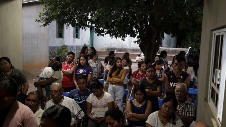 Relatives and neighbors of Evarado Ventura Hernandez pray in front...