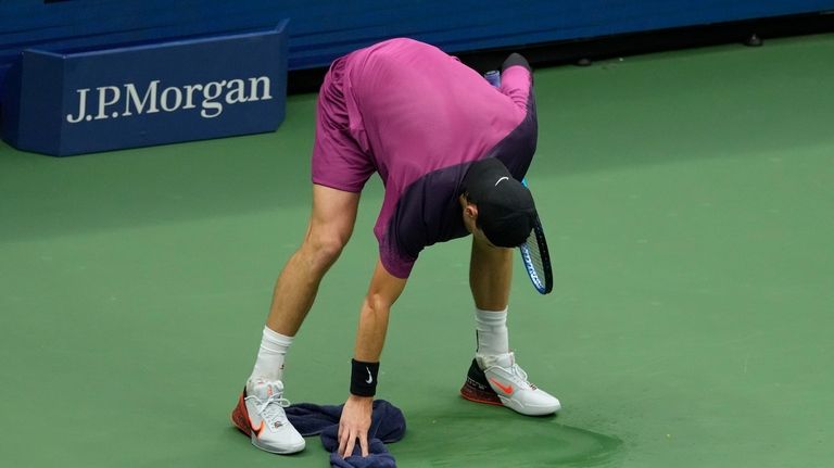 Jack Draper, of Great Britain, wipes the court against Jannik...