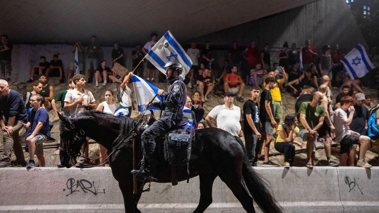 A police officer on a horse moves past a protest...