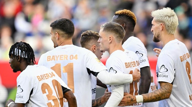 Leverkusen's goalscorer Florian Wirtz, middle celebrates with teammates after scoring...