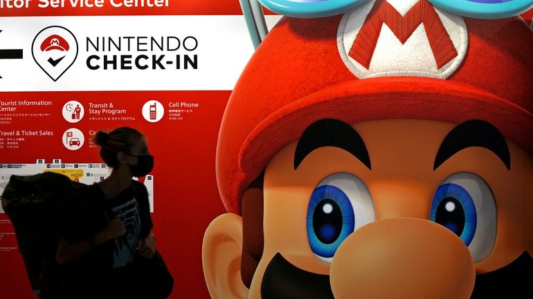 A traveler walks past an advertisement featuring a Nintendo character...