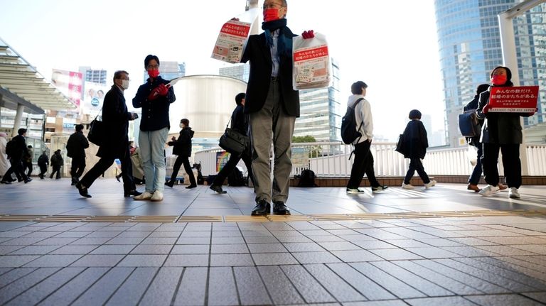 LGBTQ activists distribute chocolates to morning commuters at Shinagawa Station,...