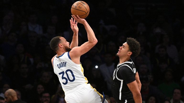 Golden State guard Stephen Curry shoots defended by Brooklyn Nets...