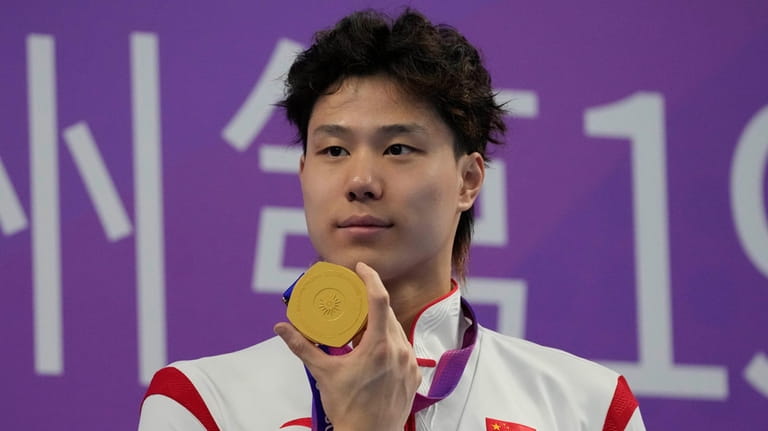 China's Qin Haiyang celebrates his gold medal for the men's...