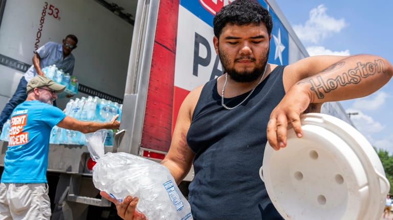 Daniel Valdez places a fresh bag of ice in a...