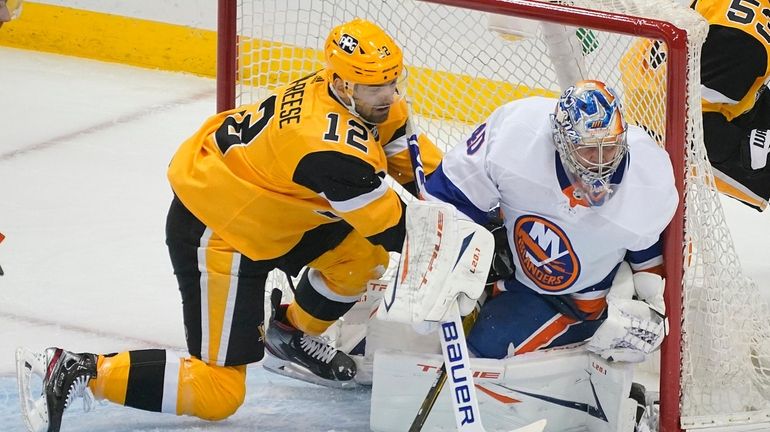 Pittsburgh Penguins' Zach Aston-Reese, left, slides into the goal behind...