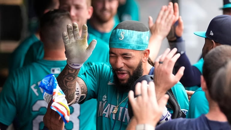 Seattle Mariners' J.P. Crawford celebrates in the dugout after his...