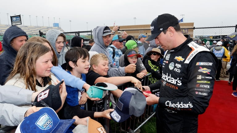 Driver Kyle Busch, right, gives autographs before a NASCAR Cup...