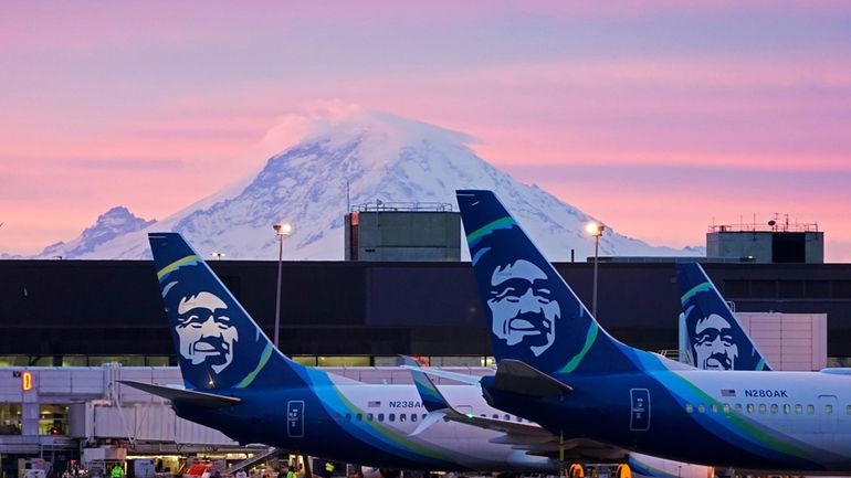 Alaska Airlines planes are shown parked at gates with Mount...