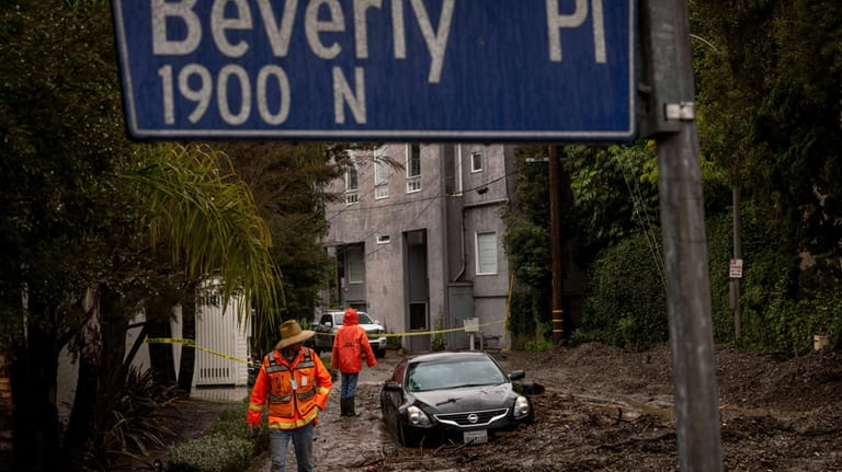 Workers survey a mudslide Tuesday, Feb. 6, 2024, in the...