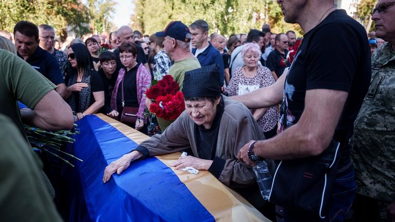 A mother cries near the coffin of her son killed...