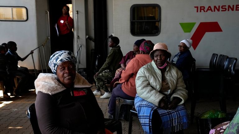 Patients queue for an eyes test, outside the Phelophepa eye...