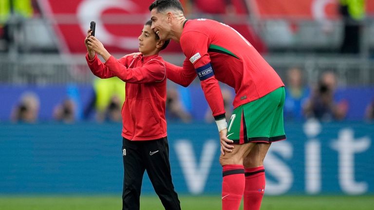 A young pitch invader takes a selfie with Portugal's Cristiano...