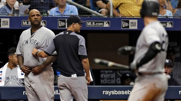 New York Yankees manager Aaron Boone, center, restrains starting pitcher...