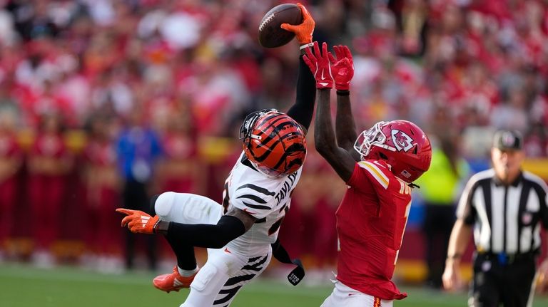 Cincinnati Bengals cornerback Cam Taylor-Britt, left, intercepts a pass intended...