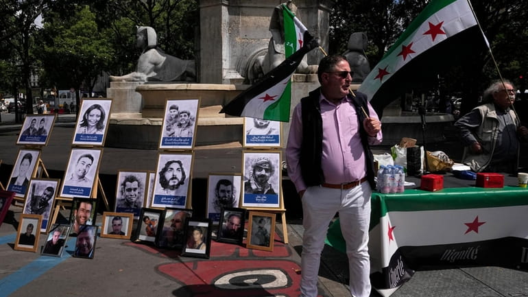 Activists hold Syrian flags next to portraits of alleged victims...