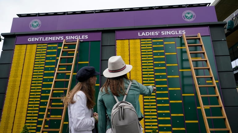 Spectators look at the order of play on day eight...