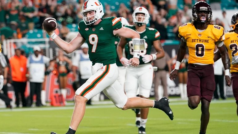 Miami quarterback Tyler Van Dyke (9) runs to score a...