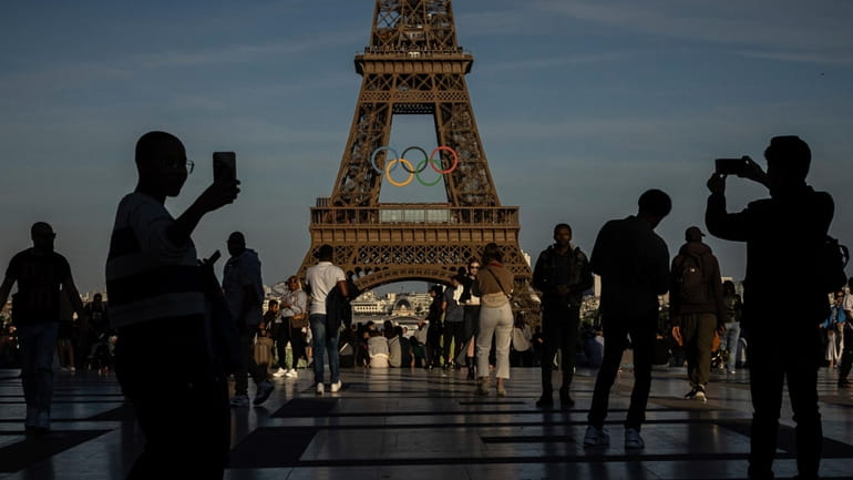 People film the Olympic rings displayed on the Eiffel Tower in...