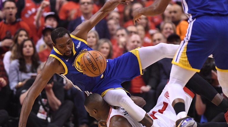 Kevin Durant, left, tumbles over Raptors center Serge Ibaka during...