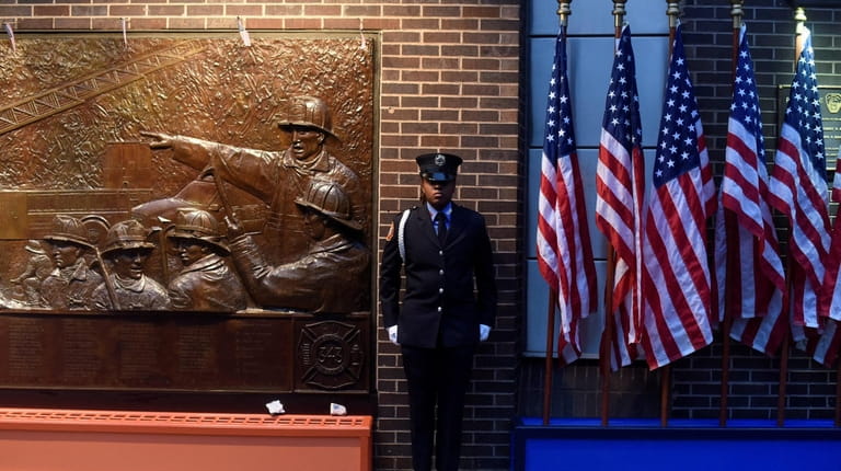 A member of the FDNY stands at attention next to...