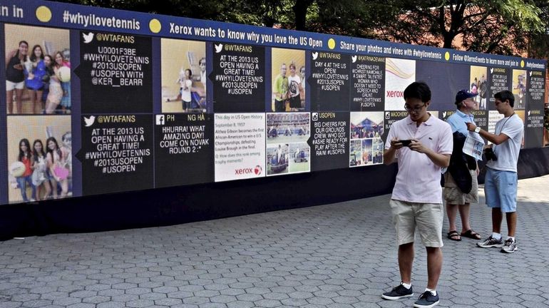 Tennis fans stop in front of a 50-inch long electronic...