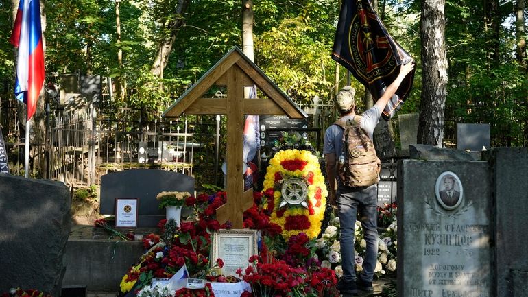 A man straightens a flag of the Wagner private military...