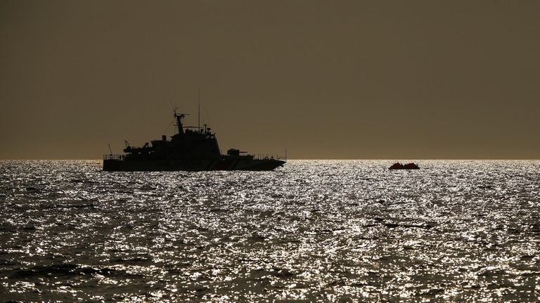 Turkish coast guard vessel approaches a life raft with migrants...