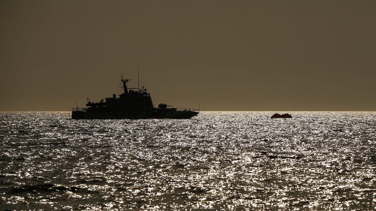 Turkish coast guard vessel approaches a life raft with migrants...