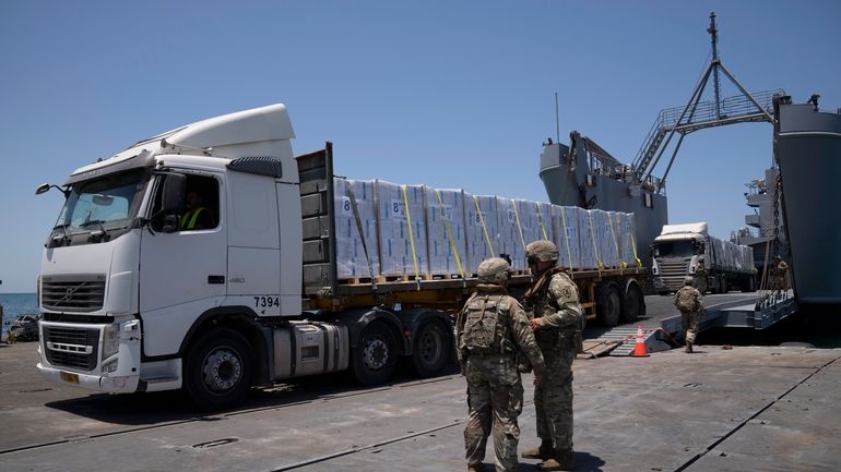 U.S. Army soldiers stand next to trucks arriving loaded with...