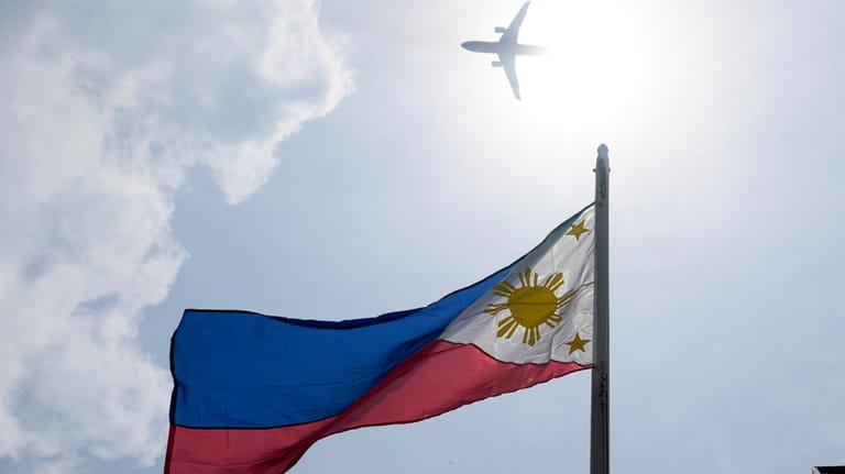 A plane flies above a Philippine flag at the Emilio...
