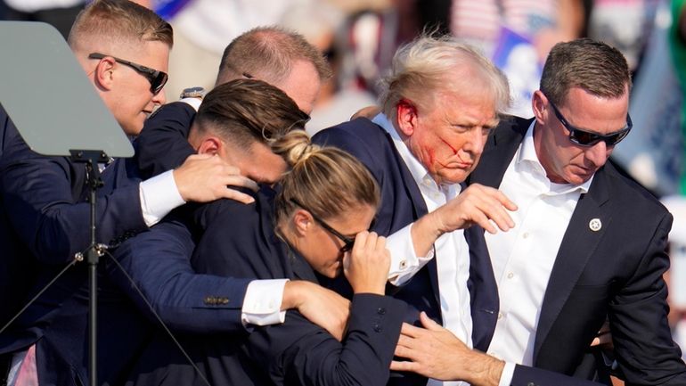 Republican presidential candidate former President Donald Trump is helped off...