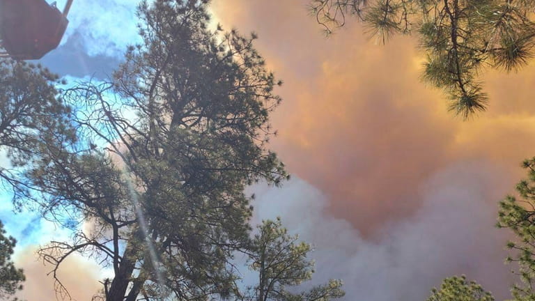 Smoke from a wildfire rises over trees in Ruidoso, N.M.,...