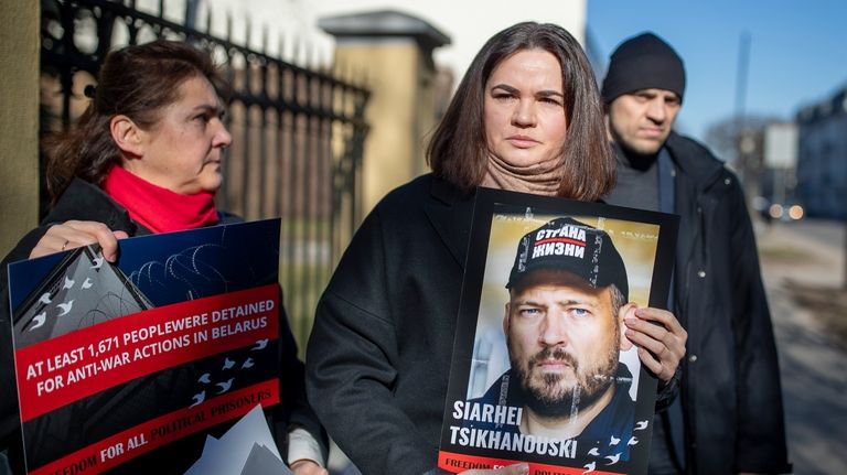 Belarusian opposition leader Sviatlana Tsikhanouskaya, center, holds a portrait of...