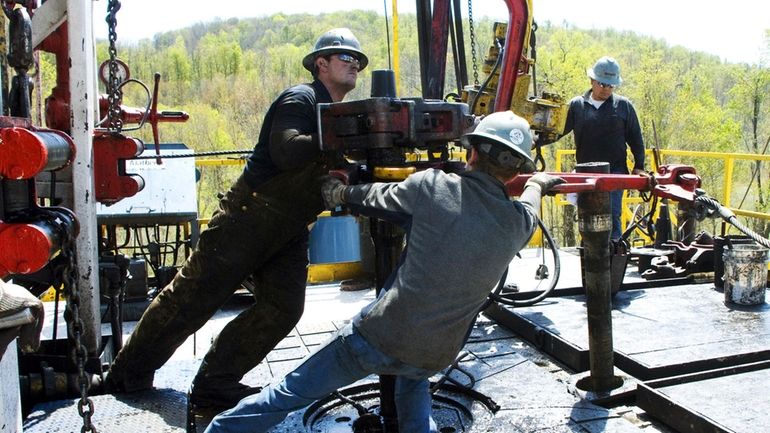 Workers move a section of well casing into place at...