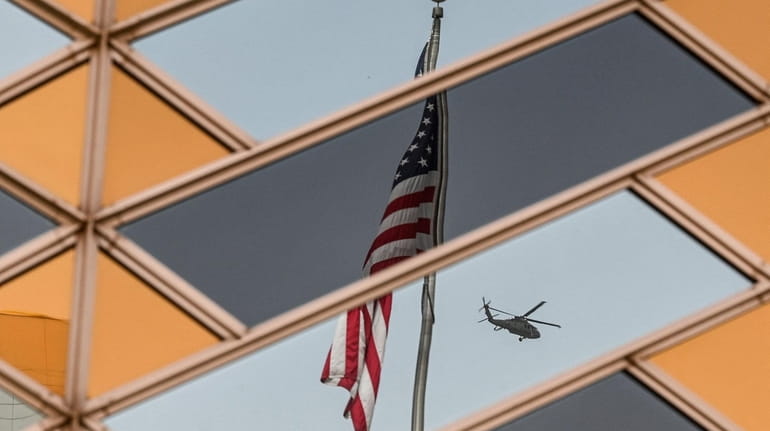 The U.S. flag is reflected in the windows of the...