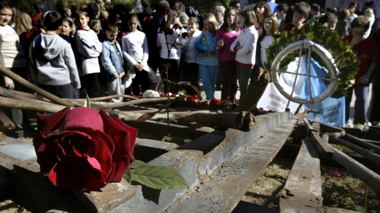 FILE -Students stand behind the wreckage of a gate at...