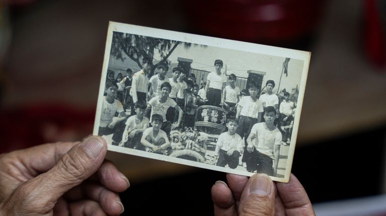 Villager Lo Yuet-ping holds up an old black and white...