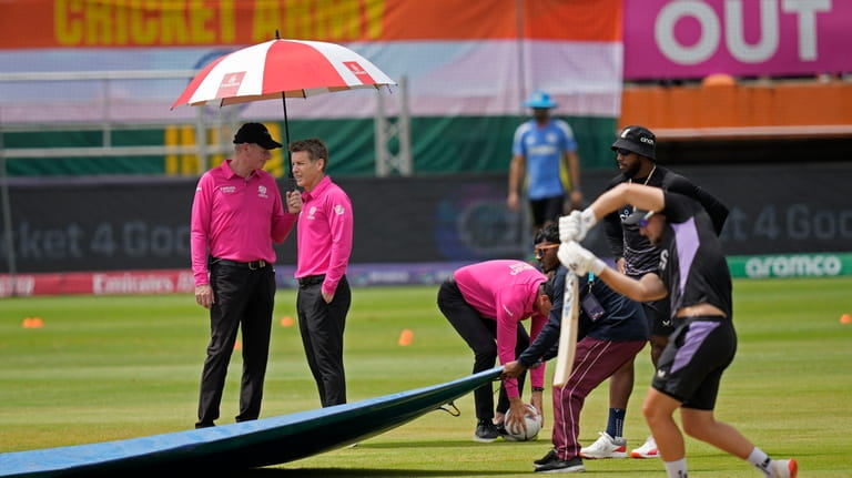 The umpires inspect the field after wet outfield delayed the...
