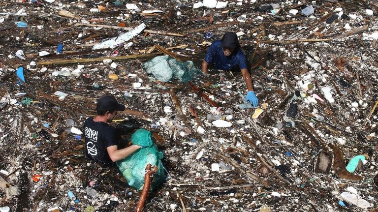 Volunteers pick up trash on a river in Pecatu, Bali,...