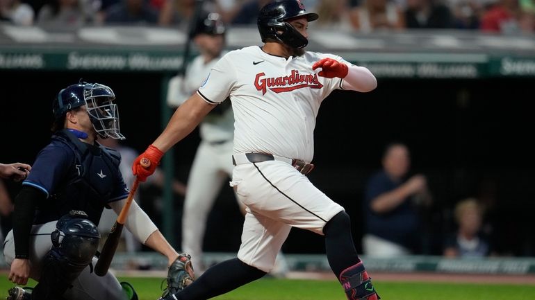 Cleveland Guardians' Josh Naylor, right, hits a single in front...